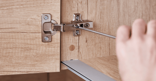 Soft close hinges being installed on a cabinet door.