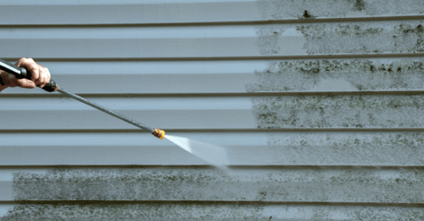 Person power washing exterior vinyl siding on house in omaha.