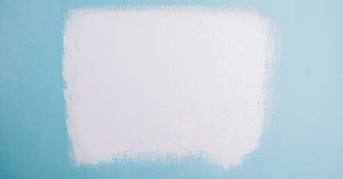 Large swatch of white paint on top of wall painted bright blue.