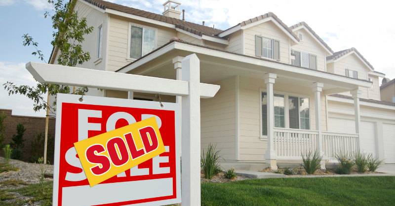 Creamy white painted house with sold sign in front yard.