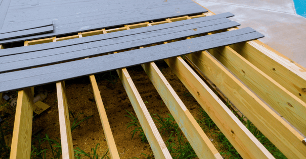 Black composite deck boards laying over wooden beams supporting a deck.