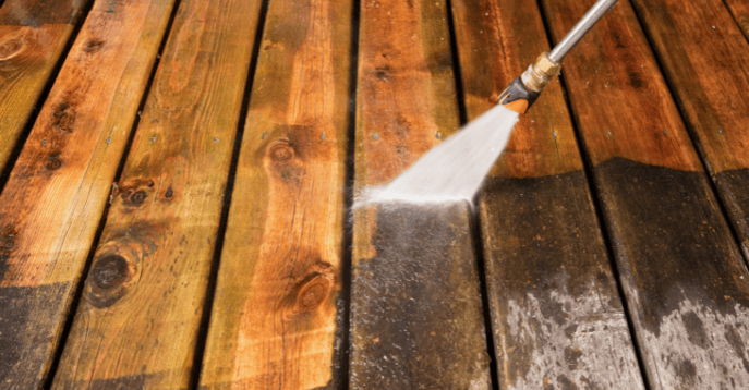 Power washer cleaning exterior wood deck that is dirty.