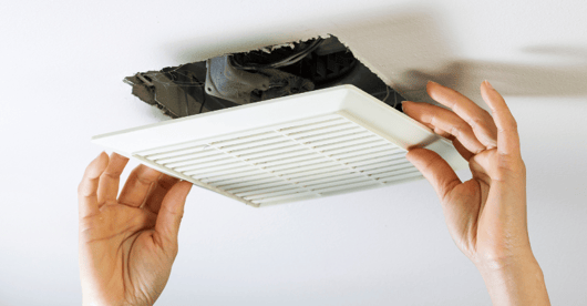 Person attaching a white vent cover to interior white ceiling.