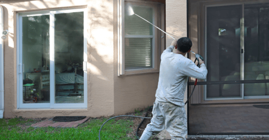 Painter power washing house in Omaha, NE.