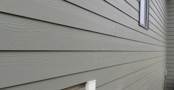 Siding of house painted muted green with wooden detail.