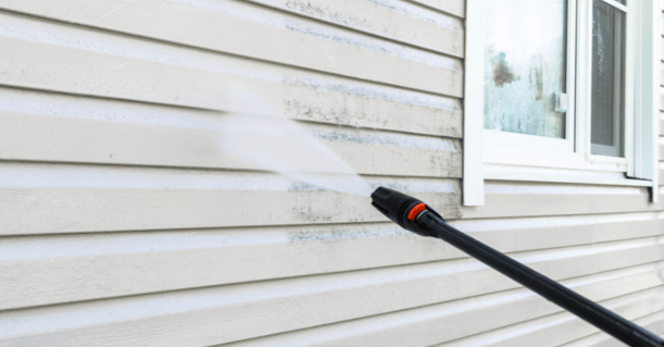 Power washer spraying a house with water before painting.