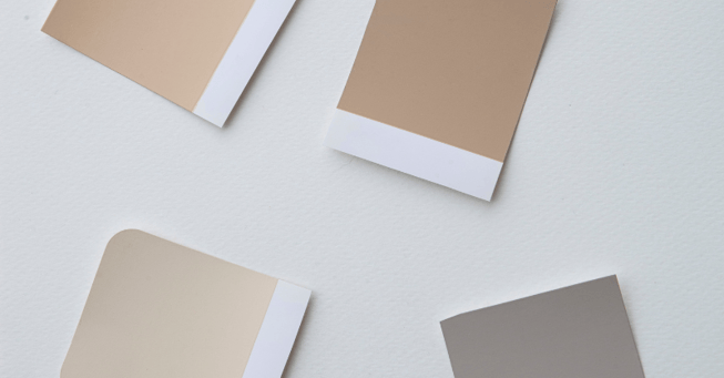 Neutral warm paint samples laid out on a table.