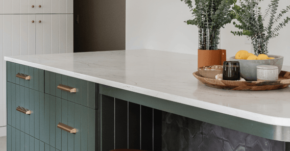 Kitchen island painted green with gold hardware.