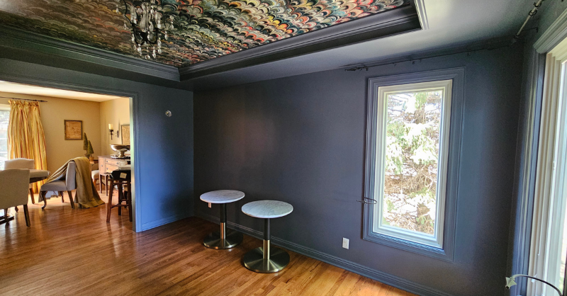 Dining room in a home in Omaha, NE painted a dark navy blue color with wallpaper on the ceiling.