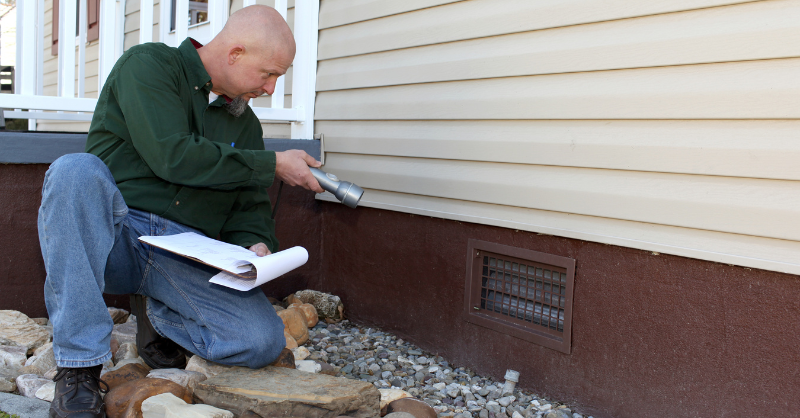Homeowner inspecting exterior foundation of a home in Omaha, NE to see if it needs painted.