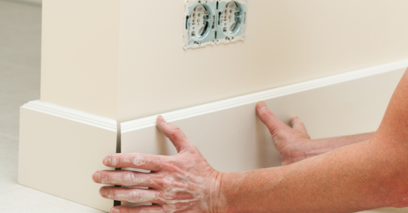 Person installing a new baseboard trim in a room at a home in Omaha, NE.