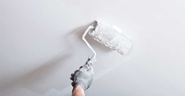 Painter rolling white paint onto a ceiling in Omaha, NE.