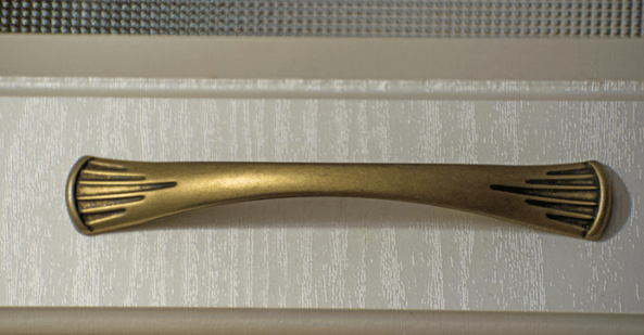 Antique brass cabinet handle on a drawer.