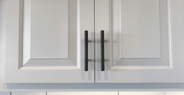 White cabinet doors with black handles in a kitchen.