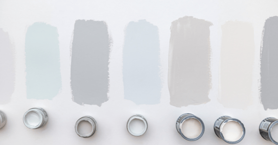 Paint samples and cans on a wall to help choose a paint color.