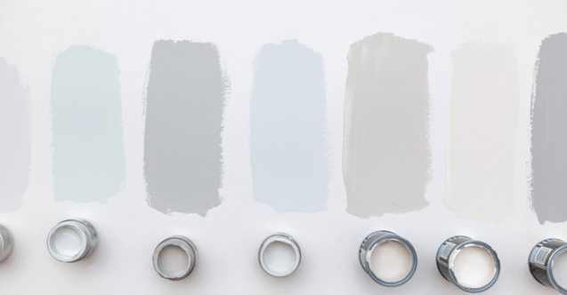 Paint colors swatched on a flat surface with paint cans.