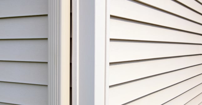 Corner of house with vinyl siding that is in a light greige color.