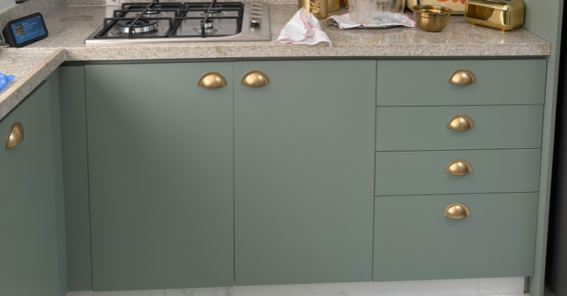 Lower metal cabinets painted a sage green color with gold handles.