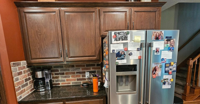 Cabinets by fridge refinished with a dark brown stain / tone in a kitchen in Omaha, NE.