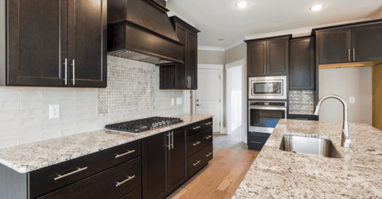Kitchen with granite countertops and dark brown cabinets with silver handles.