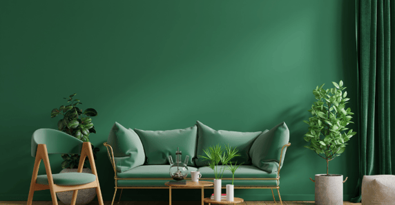 Emerald green painted wall, couch, chair. and green leafy plants in a living room.