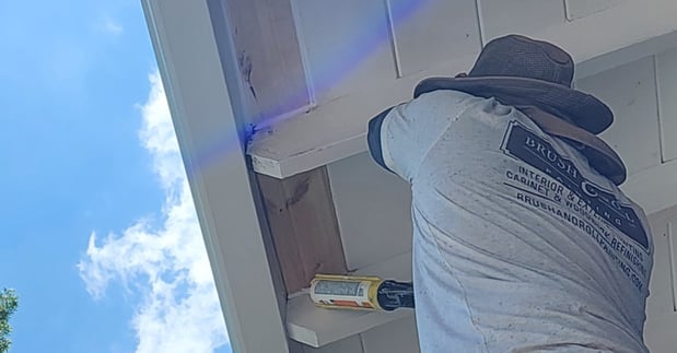 Painter caulking soffits under the roof of a home in Council Bluffs, IA.