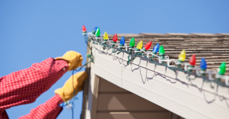 Person installing lights with clips along the roofline of a home in Omaha, NE.