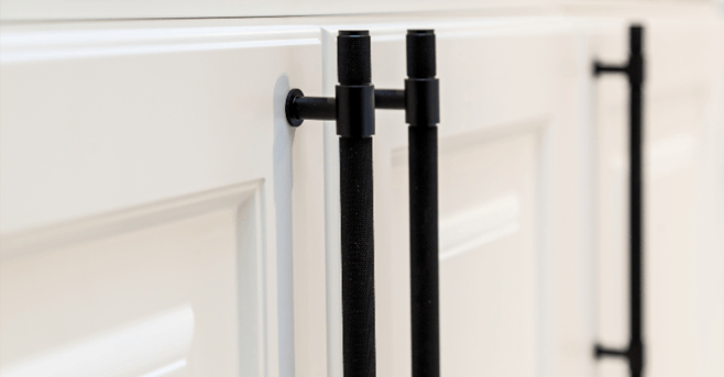 Close up of cabinet doors with long black handles.