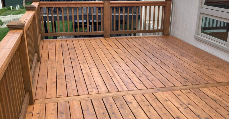 Deck stained a warm orangish tone with deck boards different shades due to the wood in Omaha.