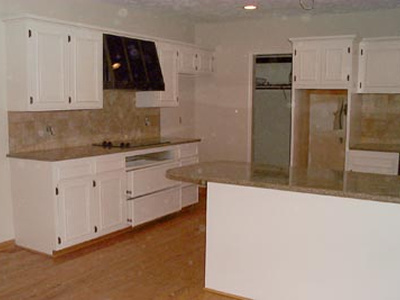 Kitchen with white cabinets and beige countertops and backsplash.