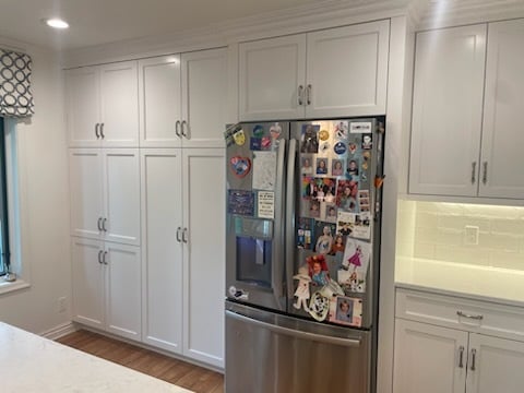 Wall of cabinet doors and a stainless steel fridge in a kitchen. The cabinets are painted white by Brush and roll painting in Omaha, NE.