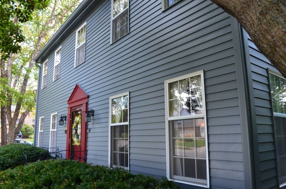 Exterior of house with blue siding, white window frames, and a red door.