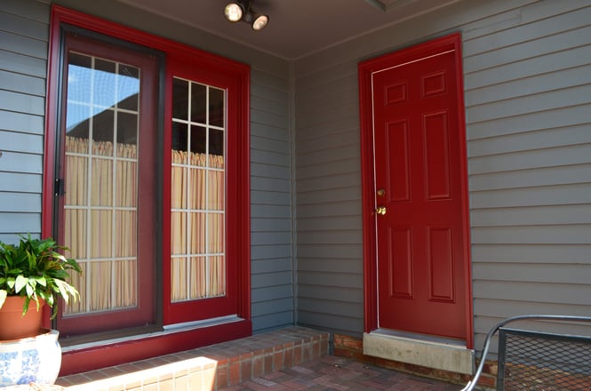 Exterior door and trim painted deep red with a cool dark blue painted siding on the exterior of a home in Omaha, NE.