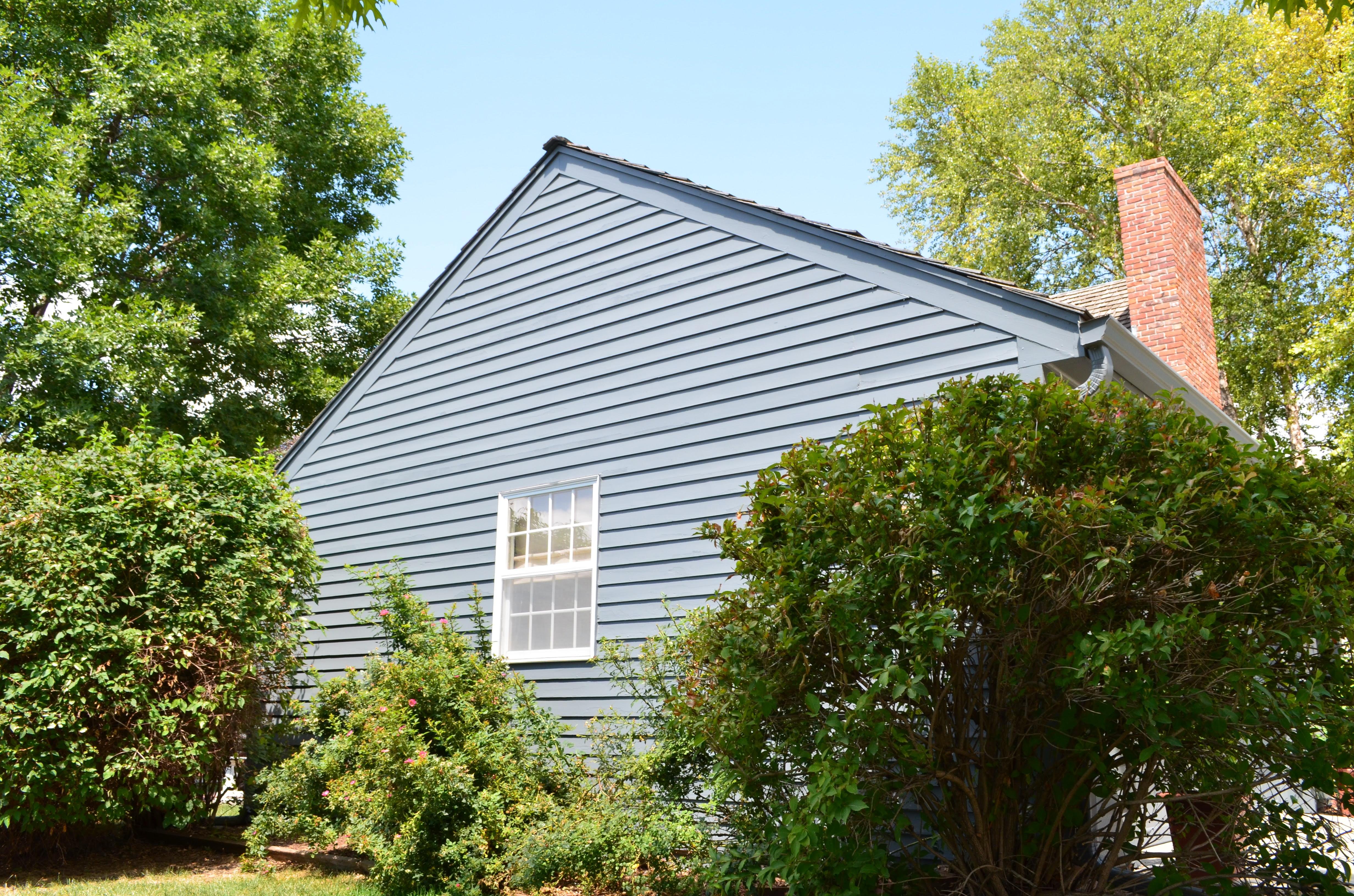 Exterior of house with vinyl siding painted a darker blue grey color in Omaha, NE.