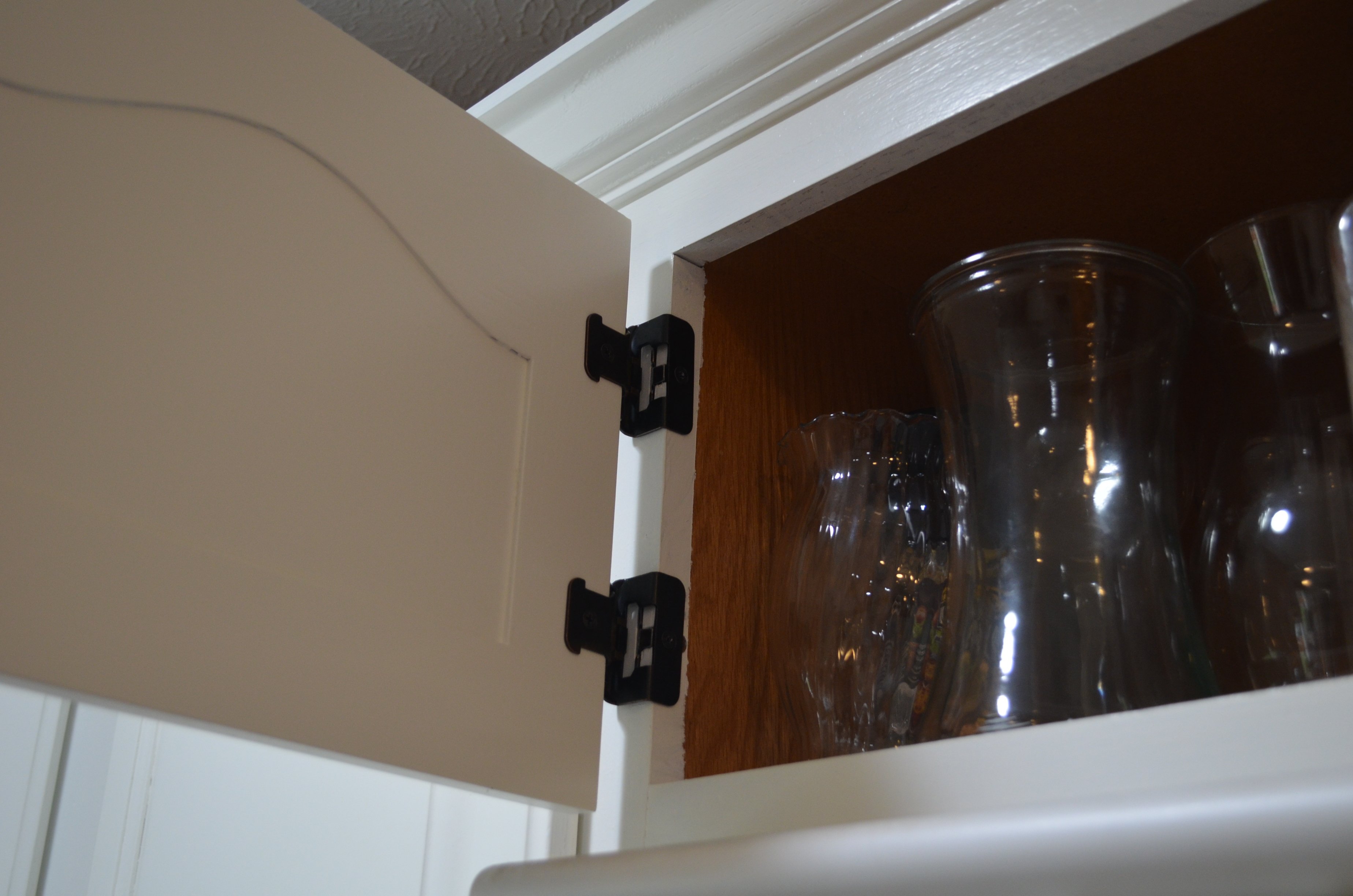 Inside of kitchen cabinet door on the hinge painted white by Brush & Roll Painting painters in Omaha, NE.
