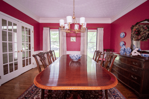 Dining room with bright red wall paint and a large wooden table.