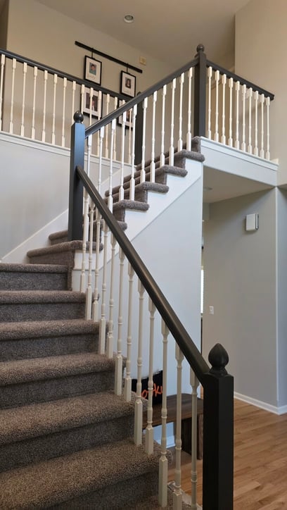 Staircase in an entryway with white painted rods and a dark stained railing.