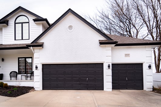 White exterior painted home with black trim and painted 3 car garage doors.