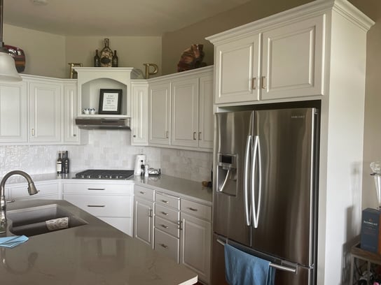 Kitchen with white cabinets and beige painted walls and white countertops and backsplash.