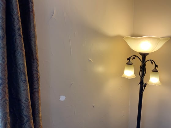 Interior beige paint on wall that is bubbling and chipping.