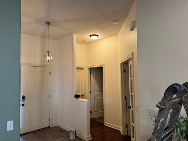 Interior home entryway painted a off white on walls with cream colored woodwork and trim.