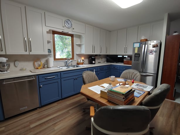 Kitchen with white upper cabinets and blue lower painted cabinets.