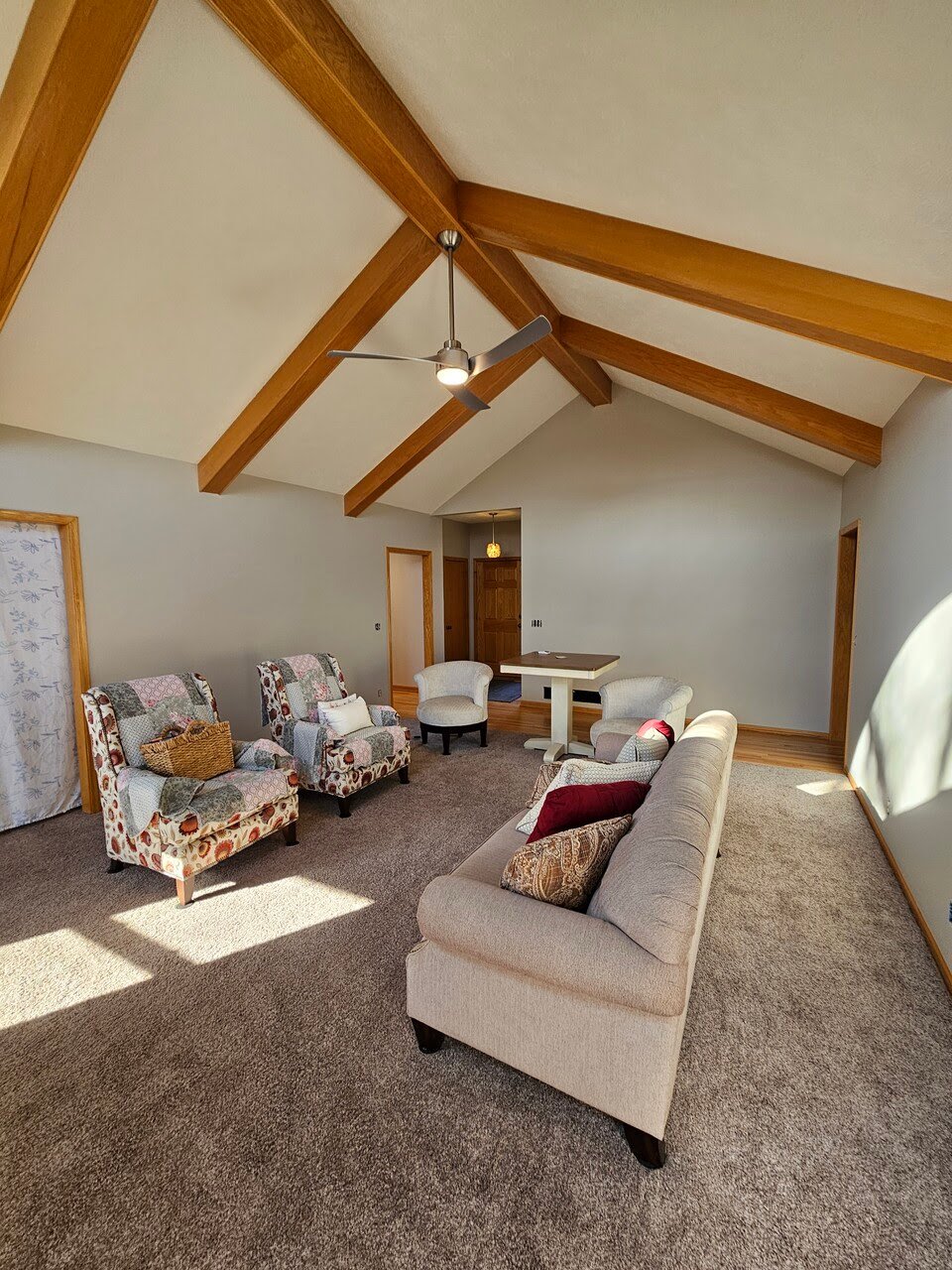 Living room with freshly painted off white, grey walls with a white ceiling and oak wood beams.