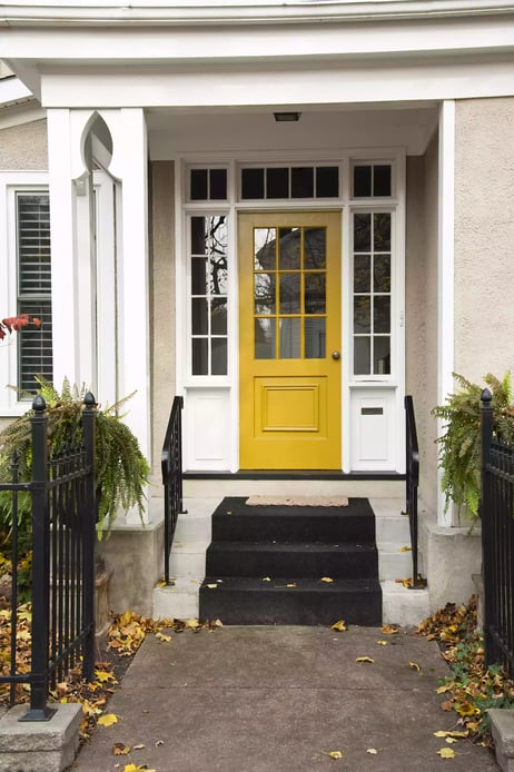 Yellow front door with white trim and beige exterior of the house.