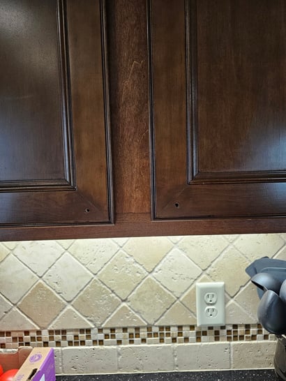 Cabinet stain on a door touched up around knobs.