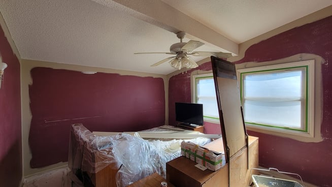 Interior bedroom being painted a beige brown from a deep maroon red paint.