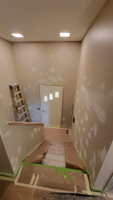 Entryway and stairs in an Omaha home with primer on walls before painting.