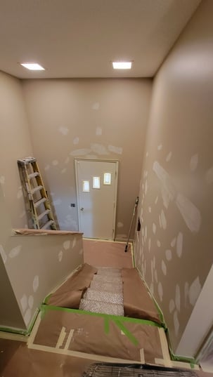 Spots along the staircase on a wall with spackle and primer, ready to paint.