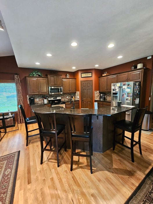 Kitchen cabinets refinished in a dark brown stain with dark red walls.
