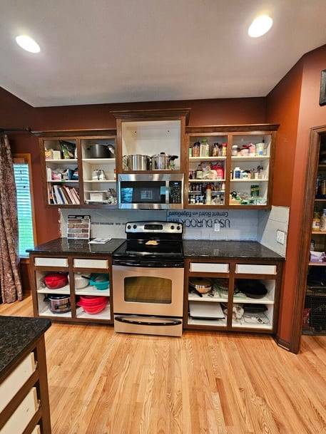 Cabinets around a stove in the process of being stained with the doors and drawer fronts missing.
